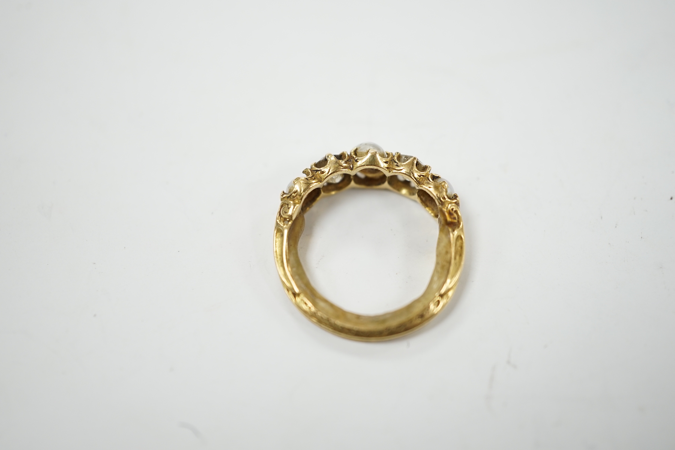 A late Victorian yellow metal and graduated three stone split pearl and two stone diamond set half hoop ring, with unusual wax? insert to the shank, size F, gross weight 3.2 grams.